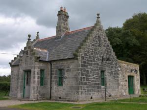 ein altes Steingebäude mit einem Kamin darüber in der Unterkunft Magherintemple Lodge in Ballycastle