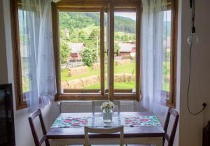 a table with a vase of flowers sitting in front of a window at Aura's Guest House in Sadova