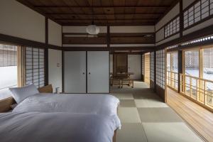 a bedroom with a bed in a room with windows at 滔々 倉敷民藝館南の宿 toutou, Mingeikan Minami no Yado in Kurashiki