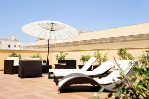 a patio with white chairs and an umbrella at Appartamenti Trapani In in Trapani