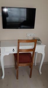a tv on top of a white desk with a chair at Yavuzlar Hotel in Safranbolu