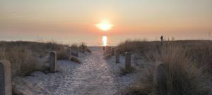 ユリウスルーにあるJuliusruh Strandparadies 1の夕日を背景にしたビーチへの道