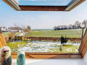 a window with a view of a field and the ocean at 4 person holiday home in Tranekær in Tranekær