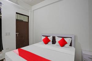 ノイダにあるHotel O NIKKU HOTELのベッドルーム1室(赤と白の枕が備わるベッド1台付)