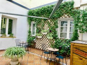 Un patio con mesas y sillas y una pared cubierta de hiedra. en Far Home Atocha, en Madrid