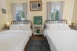 two beds in a room with two windows at Anilao Bungalows in Mabini