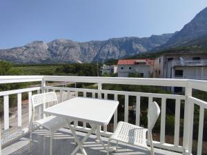 a white table and chairs on a balcony with mountains at Apart-pansion Promajna in Promajna