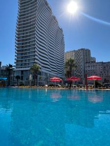 une grande piscine d'eau bleue devant un grand bâtiment dans l'établissement ORBI Residence LUXURY, à Batoumi