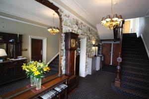 um corredor com escadas e um vaso de flores sobre uma mesa em The Coledale Inn em Keswick