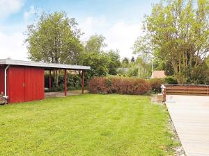 a backyard with a red shed and a grass field at 4 star holiday home in Sydals in Sarup