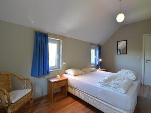 a bedroom with a white bed and a chair at Durbuy Villa with Sauna in Durbuy