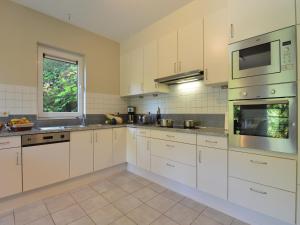 a large kitchen with white cabinets and a window at Durbuy Villa with Sauna in Durbuy