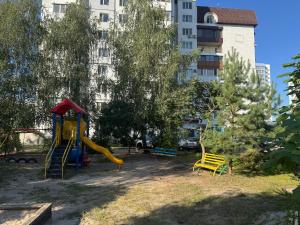 a playground with a slide in a park with a building at Затишна квартира на березі Дніпра in Cherkasy