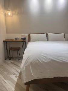 a bedroom with a large white bed and a table at DayBreak 2 in Taitung City