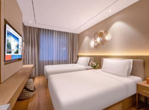 a hotel room with two beds and a flat screen tv at Orange Hotel Beijing Xisanqi Xiaomi Technology Park in Beijing