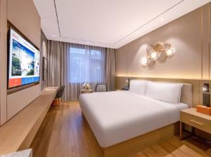 a bedroom with a large white bed and a flat screen tv at Orange Hotel Beijing Xisanqi Xiaomi Technology Park in Beijing