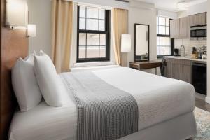 a bedroom with a large white bed and a kitchen at The Beekman Tower, Trademark Collection by Wyndham in New York +41 photos