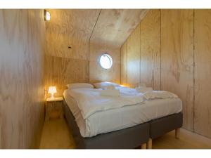 Un dormitorio con una gran cama blanca con ventana. en Tiny House in Zeeland near Oranjezon Dunes, en Vrouwenpolder