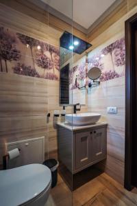 a bathroom with a white toilet and a sink at Bungalou Ikabane in Văratec