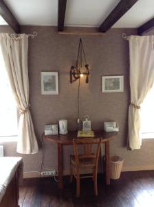 una sala da pranzo con tavolo e lampadario pendente di Aux Sources de l'Yonne a Glux