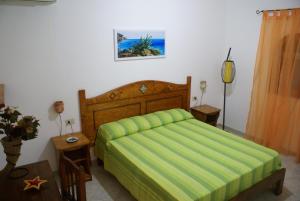 a bedroom with a bed with a green bedspread at Le Anfore Villette in Lampedusa