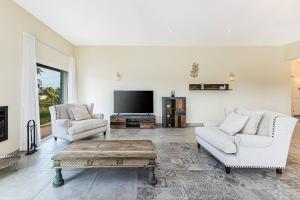 Una sala de estar con dos sofás y un televisor de pantalla plana. en Quinta dos Figos - Jacuzzi Perto da Praia, en Guia