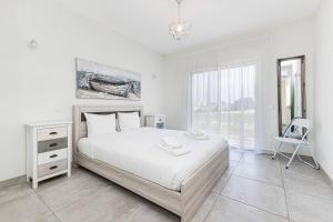 Un dormitorio blanco con una cama grande y una silla. en Quinta dos Figos - Jacuzzi Perto da Praia, en Guia 25 fotos más