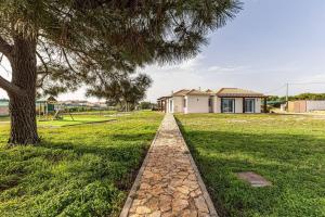 Un árbol y un camino de piedra frente a una casa. en Quinta dos Figos - Jacuzzi Perto da Praia, en Guia