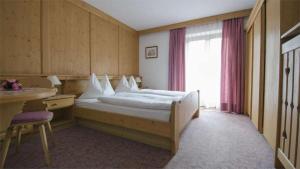 a hotel room with a bed and a window at Hotel Garni Ruscel in Santa Cristina Gherdëina