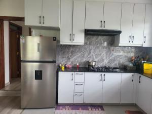 a kitchen with white cabinets and a stainless steel refrigerator at Le Tai Village Homestay in Mweiga +112 photos