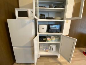 a white refrigerator with a microwave and some dishes at 絶景cottage 1棟貸切り 星空B棟 in Anazawa