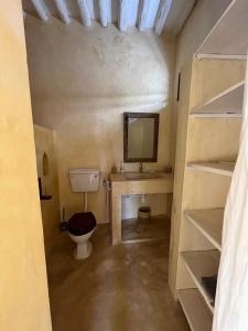a bathroom with a toilet in a room with shelves at La Joya Lamu in Shela