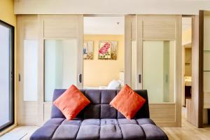 a living room with a couch with orange pillows at Noble Remix Bangkok in Bangkok