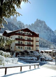 a building in the snow with mountains in the background at Hotel Letizia in San Martino di Castrozza