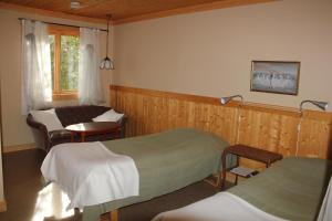 a bedroom with two beds and a chair and a window at KynnefjällsNatur in Hedekas