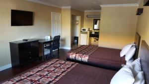 a hotel room with a bedroom with a desk and a bed at Anaheim Astoria Inn & Suites in Anaheim