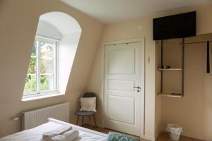 a bedroom with a bed and a window and a door at Jädra Gårdshotel in Enköping