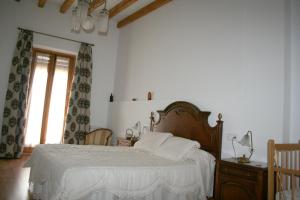 a bedroom with a bed with white sheets and a window at La Casona de Mahora in Mahora