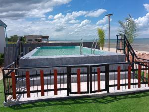 a swimming pool with a fence and the beach at Maruay villa beach in Suratthani