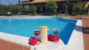 カスティリオーネ・デル・ラーゴにあるHotel Duca Della Corgnaの- ワイングラス2杯、プールサイドのテーブルのキャンドル