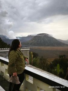 a woman standing on a balcony looking at a mountain at Tengger Bromo Villa in Ngadisari