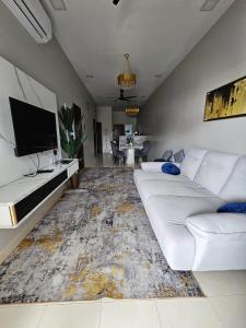a living room with a white couch and a tv at Santai Homestay PD in Port Dickson