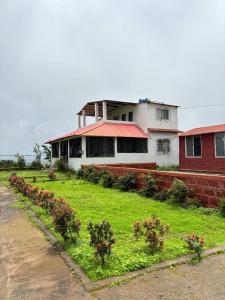 a building with a yard with plants in front of it at Silver Oak Mahabaleshwar in Mahabaleshwar +6 photos