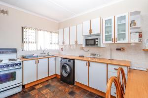 a kitchen with white cabinets and a washer and dryer at Natspat 14 in Margate