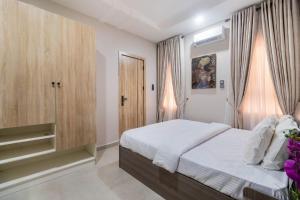 a bedroom with a bed with white sheets and curtains at 3 Bedroom Duplex for Shortlet in Ikota +4 photos