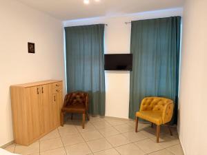 a room with two chairs and a cabinet and a television at Victory Apartments in Leoben
