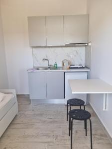 a kitchen with white cabinets and a table and two stools at Sunset Apartments & Studios in Limenaria