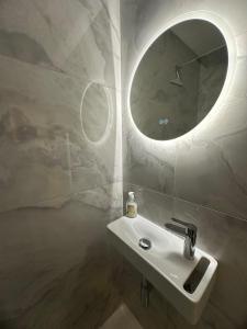 a bathroom with a sink and a round mirror at New, modern and bright studio in Neuilly-sur-Seine