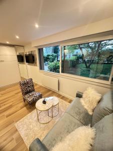 Una sala de estar con un sofá y una mesa y una ventana grande. en New, modern and bright studio, en Neuilly-sur-Seine