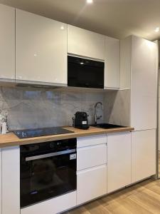 a kitchen with white cabinets and black appliances at New, modern and bright studio in Neuilly-sur-Seine +19 photos